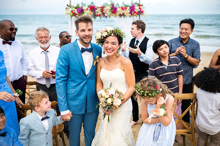 Bride and groom smiling at beach wedding surrounded by guests, highlighting dream wedding inheritance and money dispute. Bride and groom smiling at beach wedding surrounded by guests, highlighting dream wedding inheritance and money dispute.