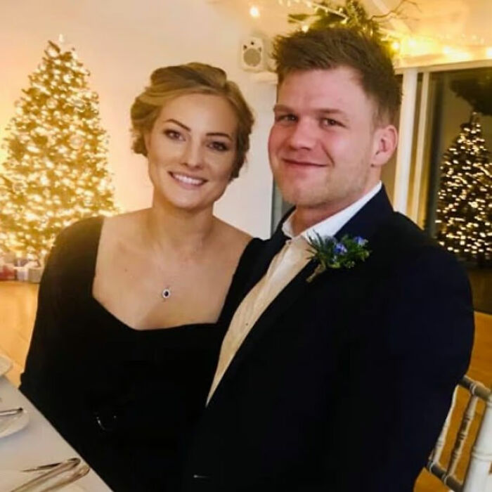 Smiling woman and man dressed formally seated at a table with Christmas trees and lights in the background. Smiling woman and man dressed formally seated at a table with Christmas trees and lights in the background.