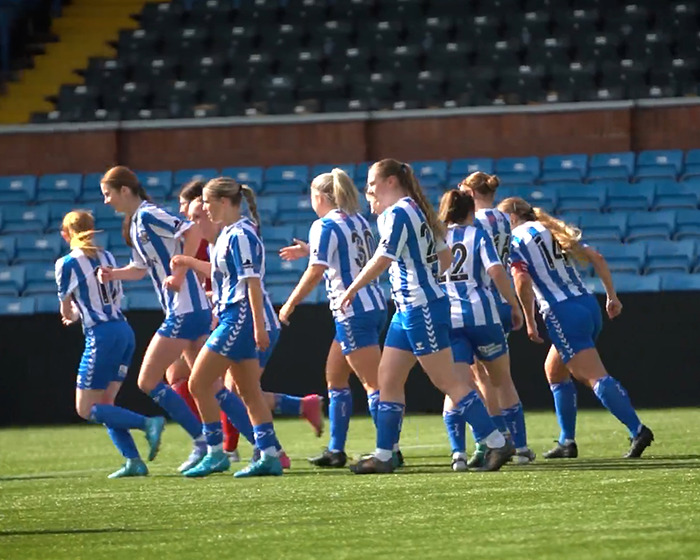 Female soccer team celebrating on the field after new signing announcement amid trolls targeting her appearance