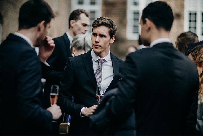 A group of well-dressed people using social cheat codes during a formal outdoor networking event.
