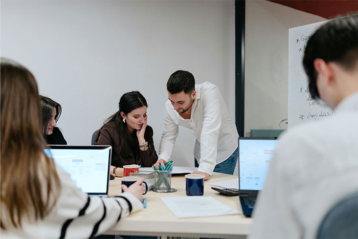 A group of people collaborating in an office setting, practicing social cheat codes through observation and teamwork.