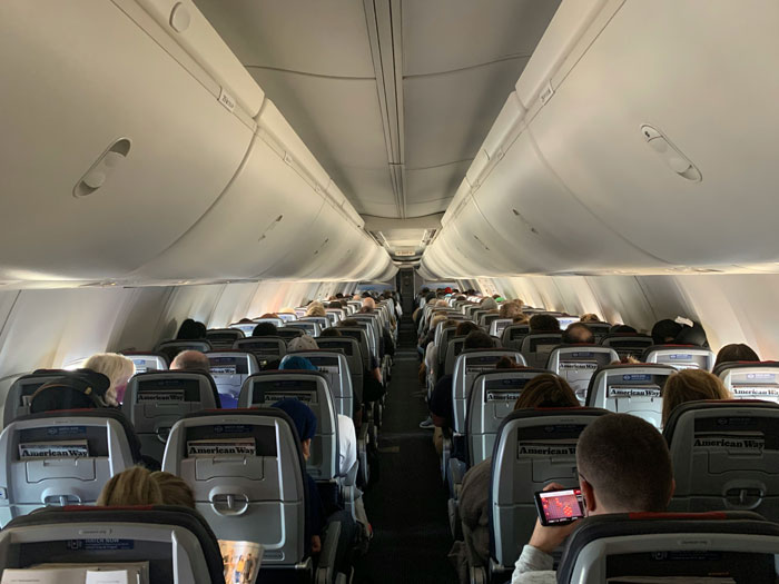 Airplane interior with passengers seated, illustrating airline controversy over new rule affecting plus-size passengers. Airplane interior with passengers seated, illustrating airline controversy over new rule affecting plus-size passengers.