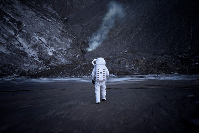 Astronaut exploring a dark, rocky terrain with smoke rising, highlighting how space is scarier than we think.