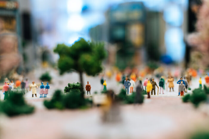 Miniature figures of people in a park with blurred trees and buildings, illustrating space is scarier than we think.