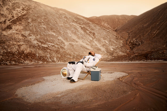 Astronaut resting in barren alien landscape, illustrating how space is a lot scarier than we think with terrifying facts.