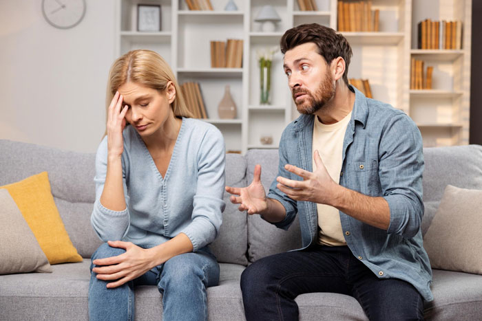 Couple having a tense conversation on sofa with woman on a 12-month hiatus from work expecting more money than &pound;150 weekly.