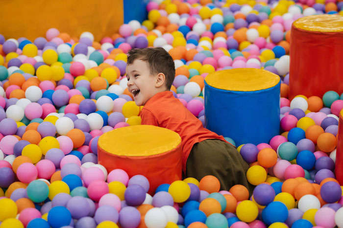 Young child playing in a colorful ball pit, representing woman on a 12-month hiatus from work and financial expectations.
