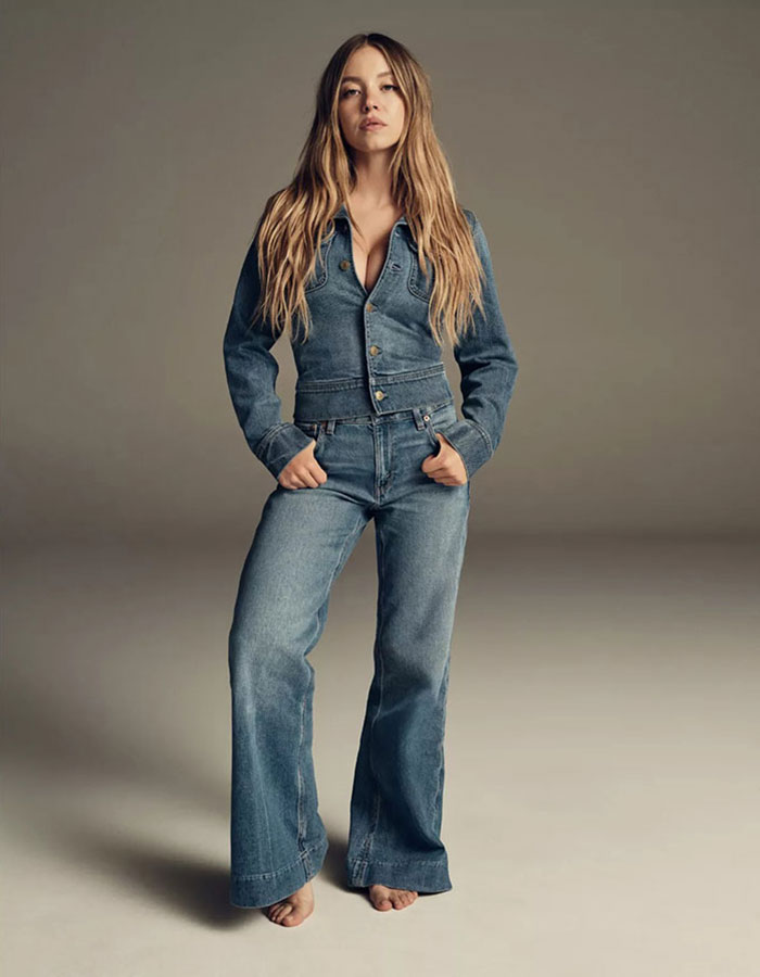 Sydney Sweeney posing barefoot in denim jacket and jeans, showcasing a bold fashion choice amid genes with bad taste discussions.