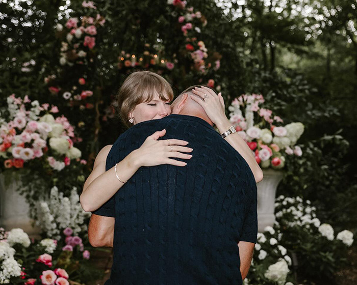 Taylor Swift and Travis Kelce hugging warmly in a floral garden, showing body language expert insights on their connection.