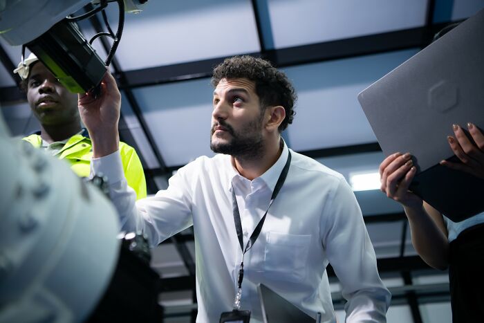 Man in a white shirt inspecting machinery, symbolizing the success of the smartest kids in their class careers.