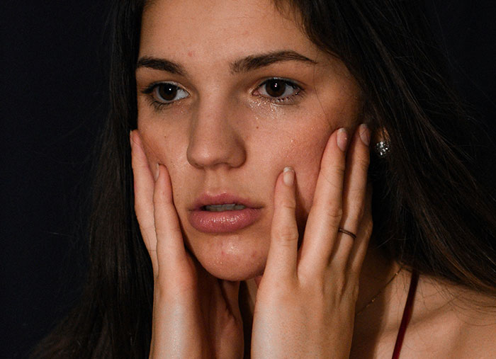 Woman with tear-streaked face holding her cheeks, showing emotional frustration reflecting wild times Walmart employees face at work.