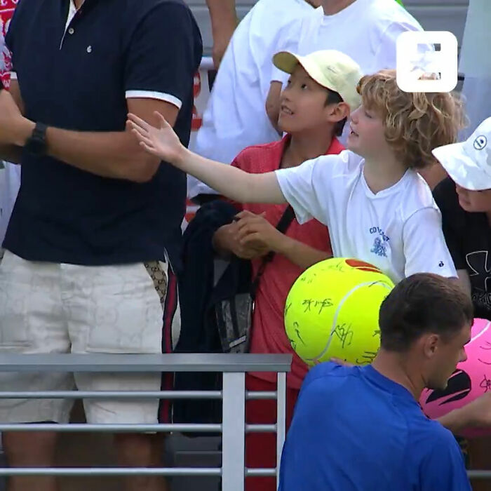 Man snatches Kamil Majchrzak's hat from kid at US Open, tennis star interacting with fans holding signed tennis balls.