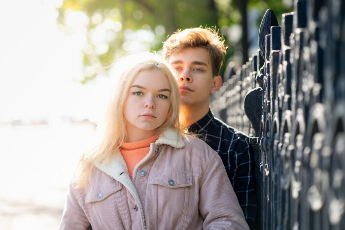 Teenage girl and boy standing close by a fence, reflecting on childhood memories that felt sweet but later unsettling.