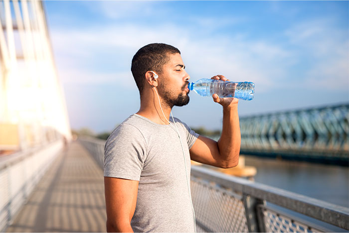 Man drinking water by bridge outdoors, illustrating common pseudoscience and scams related to health trends.