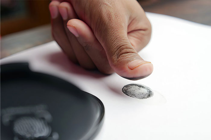 Close-up of a person’s finger pressing on a fingerprint pad, illustrating concepts related to pseudoscience and scams.