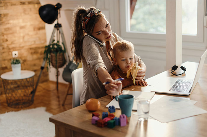 Woman multitasking with a toddler at home, highlighting challenges people point out about pseudoscience and scams.