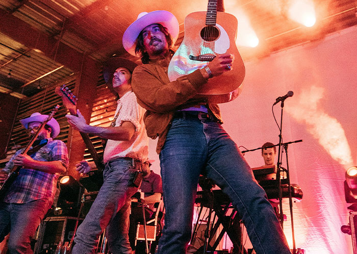 Band performing live on stage with guitars and keyboard, capturing energy and passion in a music concert setting.