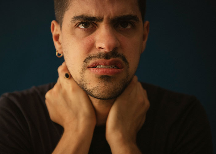 Young man with a worried expression holding his neck, illustrating emotions related to things not mentioned after marriage.