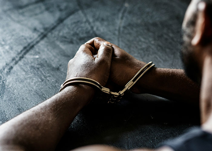 Close-up of a person with hands cuffed on a dark surface, symbolizing unexpected challenges after marriage.