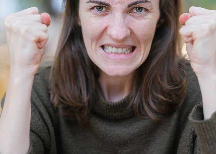 Angry woman with clenched fists and gritted teeth expressing frustration related to things not mentioned until after marriage.