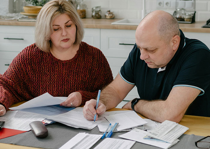 Couple reviewing documents together at a kitchen table, discussing important things not mentioned until after marriage.