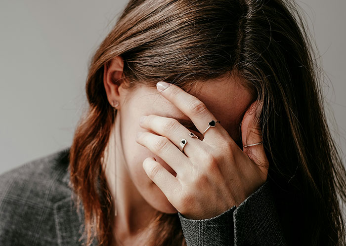 Woman covering her face with hand, displaying rings, conveying emotions related to things not mentioned until after marriage.