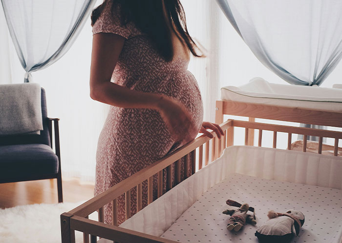 Pregnant woman standing next to a crib in a softly lit nursery, symbolizing unexpected changes after marriage.