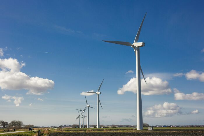 Row of wind turbines on farmland under a partly cloudy sky illustrating modern life aspects nearing breakdown