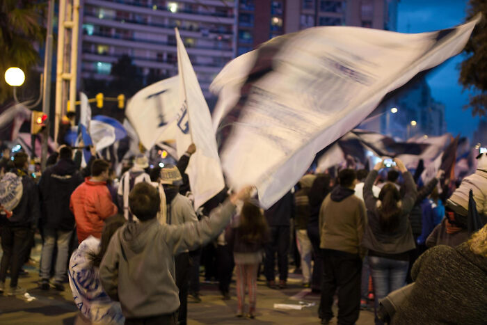 Crowd gathered at night waving large flags during a ticking big lifetime event celebration in the city streets.