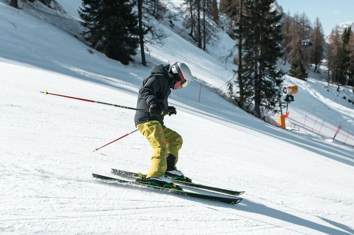 Skier in yellow pants and helmet navigating snowy slope with trees, illustrating unhinged hacks done land job concept.