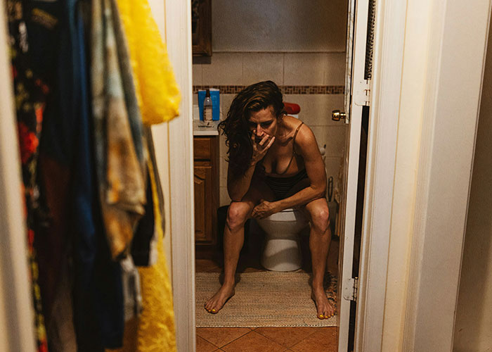 Woman sitting on toilet appearing distressed and appalled, reflecting emotional reaction to dad’s response to dead grandchild news. Woman sitting on toilet appearing distressed and appalled, reflecting emotional reaction to dad’s response to dead grandchild news.