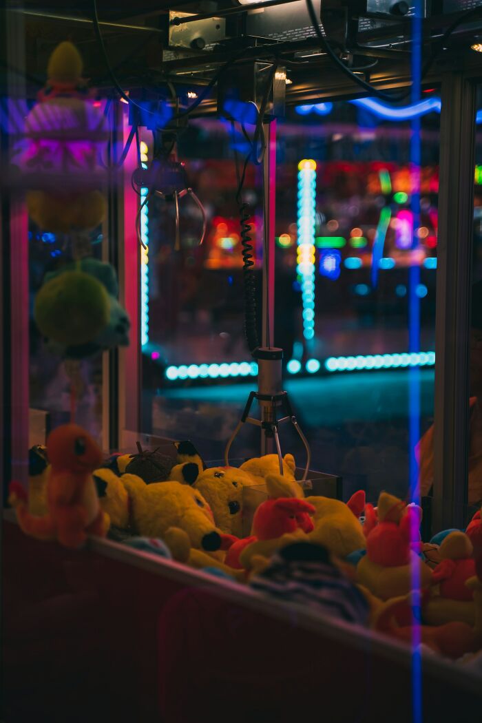 Claw machine filled with plush toys in an arcade lit by colorful neon lights, capturing a heartwarming and playful scene.