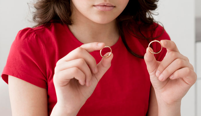 Young woman in a red shirt holding two gold rings, representing one of the most common tourist traps.