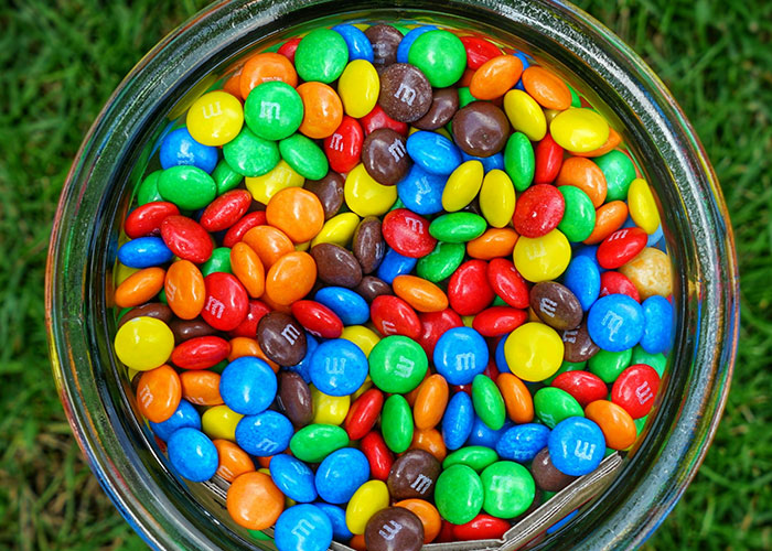 Colorful candies in a glass bowl representing a playful treat for kids being babysat and trained by a woman outdoors. Colorful candies in a glass bowl representing a playful treat for kids being babysat and trained by a woman outdoors.