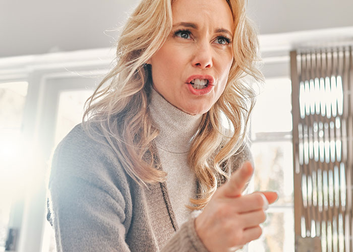 Woman pointing and speaking firmly indoors, showing determination to train cousin’s kids after being forced to babysit. Woman pointing and speaking firmly indoors, showing determination to train cousin’s kids after being forced to babysit.