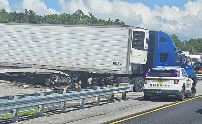 Truck involved in a fatal illegal U-turn accident with sheriff vehicle on highway shoulder during daylight.