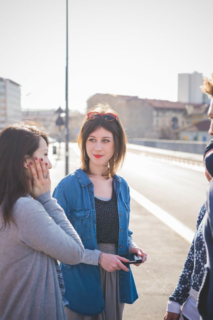 Three young people engaged in a candid conversation outdoors, illustrating stories of people getting savagely rejected.