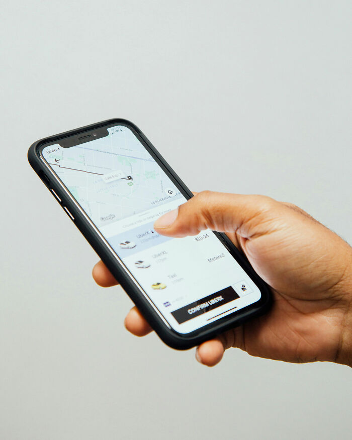 Person holding a smartphone showing an Uber app screen with ride options and map navigation.