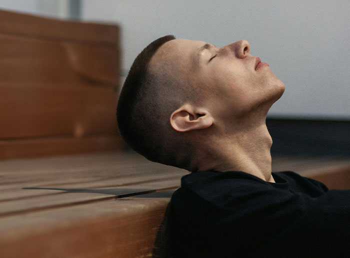 Young man sitting alone with eyes closed, reflecting on terrifying spooky encounters that still haunt him today.