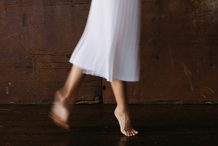 Person in white flowing dress captured mid-step on wooden floor, evoking eerie and spooky encounters still haunting today.