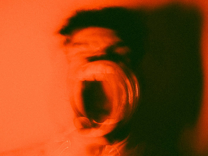 Blurred person screaming in dark red lighting representing terrifying and spooky encounters that still haunt people today.