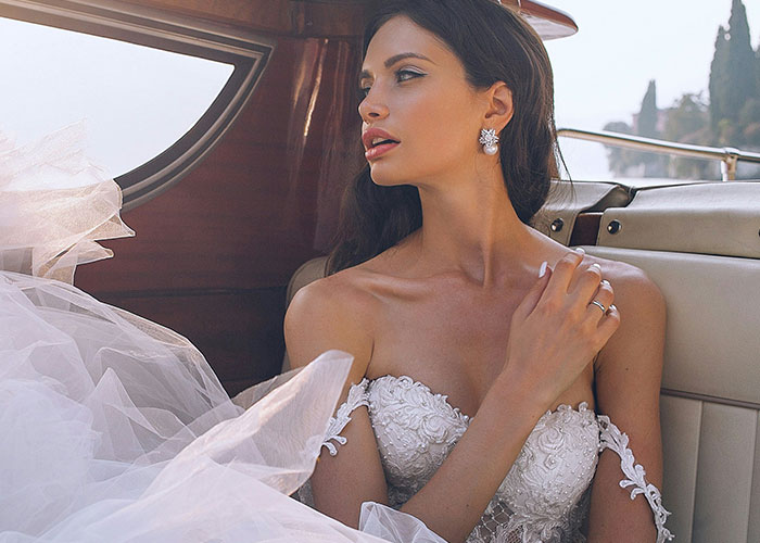 Bride wearing an elegant wedding dress sitting in a car, looking outside with a thoughtful expression about unhinged MILs comments.