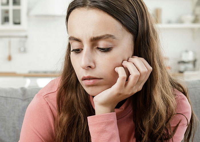 Young woman looking down thoughtfully, illustrating reactions to unhinged things MILs thought were appropriate to say out loud.