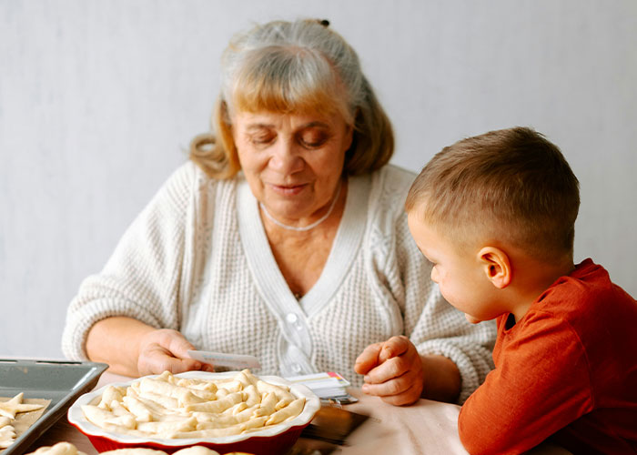 Elderly woman and young boy baking together, illustrating unhinged things MILs thought were appropriate to say out loud.