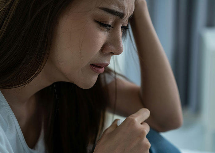 Young woman upset and crying indoors, illustrating emotional impact of unhinged things MILs said out loud.
