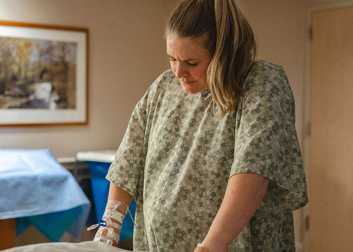 Woman in hospital gown looking down with concern, illustrating unhinged things MILs thought were appropriate to say out loud.