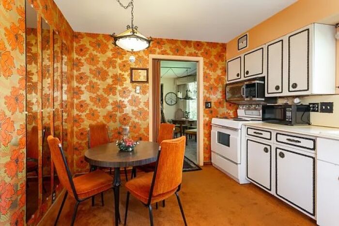 Vintage kitchen interior with orange floral wallpaper and mid-century style chairs in June Cleavers vintage closet style.