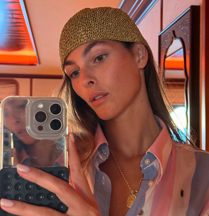 Woman taking a selfie on a yacht with warm lighting during Leonardo DiCaprio's PDA-filled yacht trip with girlfriend.