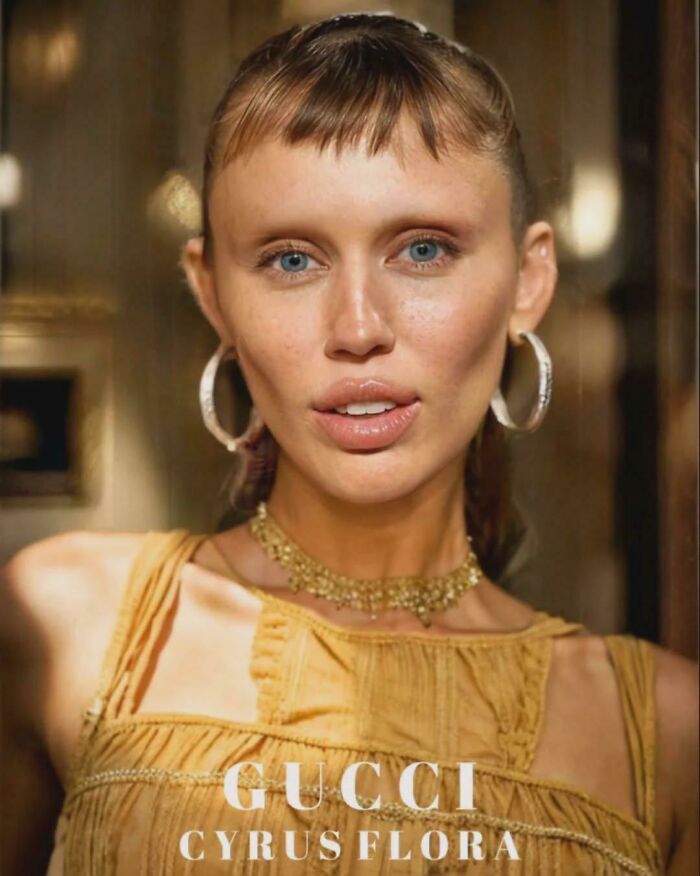 Close-up of a woman with minimal eyebrows wearing hoop earrings and a yellow top, highlighting the trend of no eyebrows.