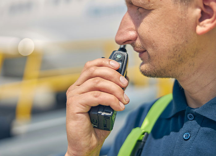 Walmart employee using a walkie-talkie outside, capturing challenging moments that make them rethink their pay.